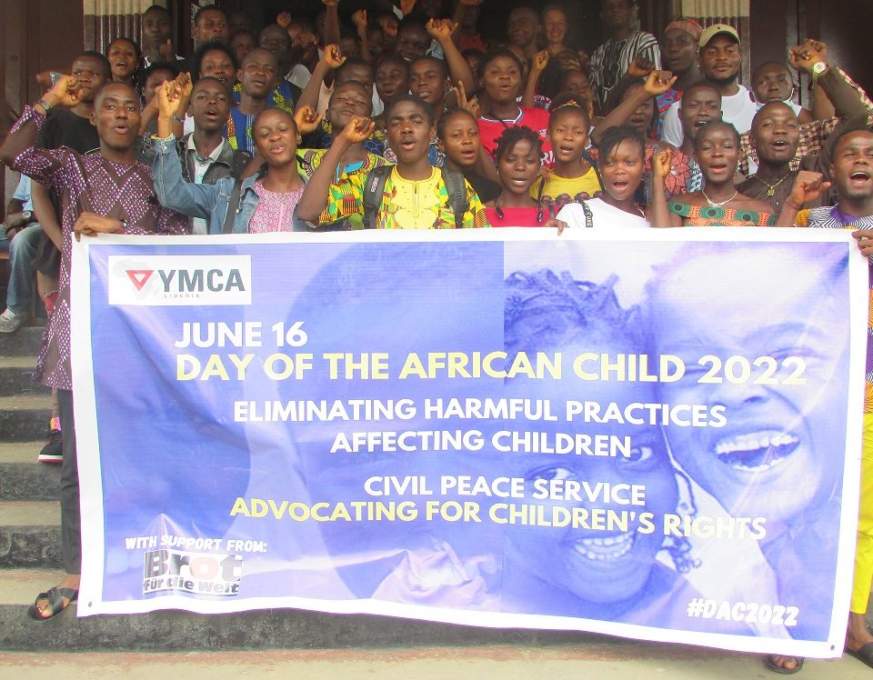 Children in front of the YMCA with a banner depicting the theme of the Day of the African Child