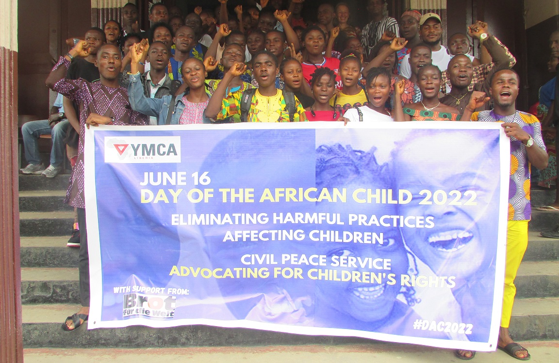 Children in front of the YMCA with a banner depicting the theme of the Day of the African Child